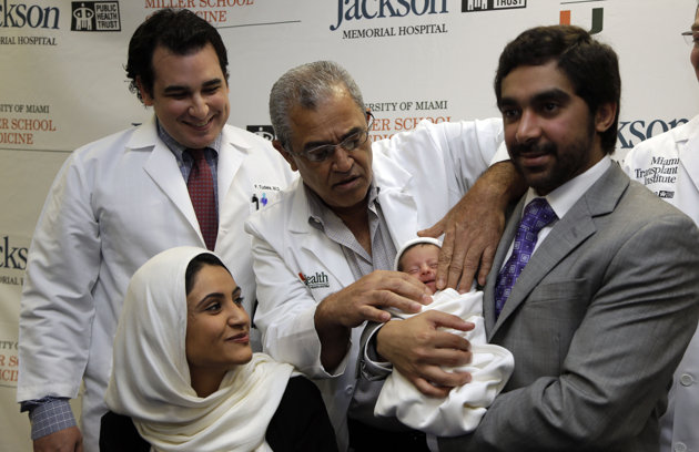 Fatema Al Ansari of Qatar, left, front, looks on as Dr. Salih Yasin, second from left, adjusts the clothing of her baby Alkadi Alhayal, center, held by her husband Khalifa Alhayal, right, during a news conference at Jackson Memorial Hospital, Wednesday, March 13, 2013, in Miami. Al Ansari was diagnosed with a condition called mesenteric thrombosis at age 19, causing her abdominal organs to fail. She is the first multivisceral transplant patient in the world to conceive and give birth. (AP Photo/Lynne Sladky)